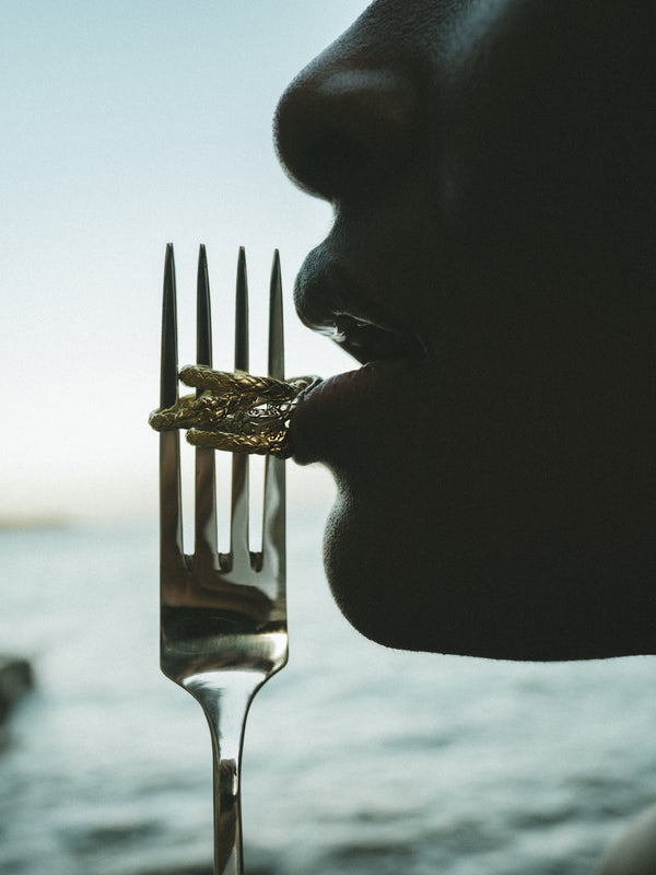 Editorial styled shot of Ouroboros Rings in white and yellow solid gold by Pola Jewellery, stacked on a fork — creative fine jewellery photography, eternal love snake rings designed in Mallorca.